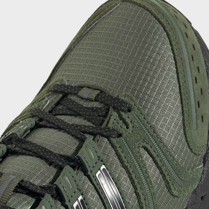 Nærbillede af tåparti, paneler og sorte snørebånd på Adidas Adistar Control 5 i Base Green.