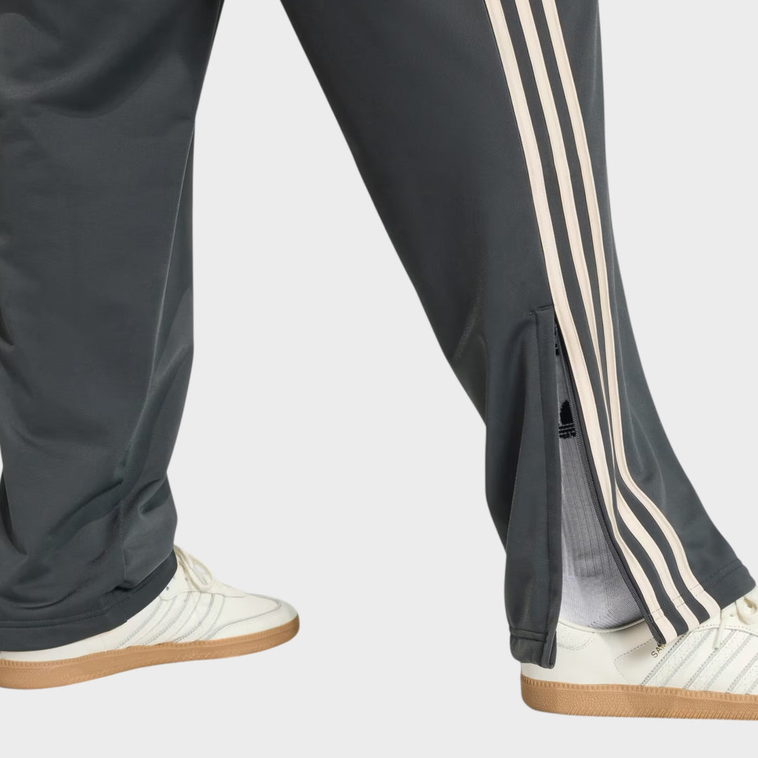 Nærbillede af materialet på Adidas Firebird Trackpants i Charcoal og Cream White med glat og behagelig kvalitet.