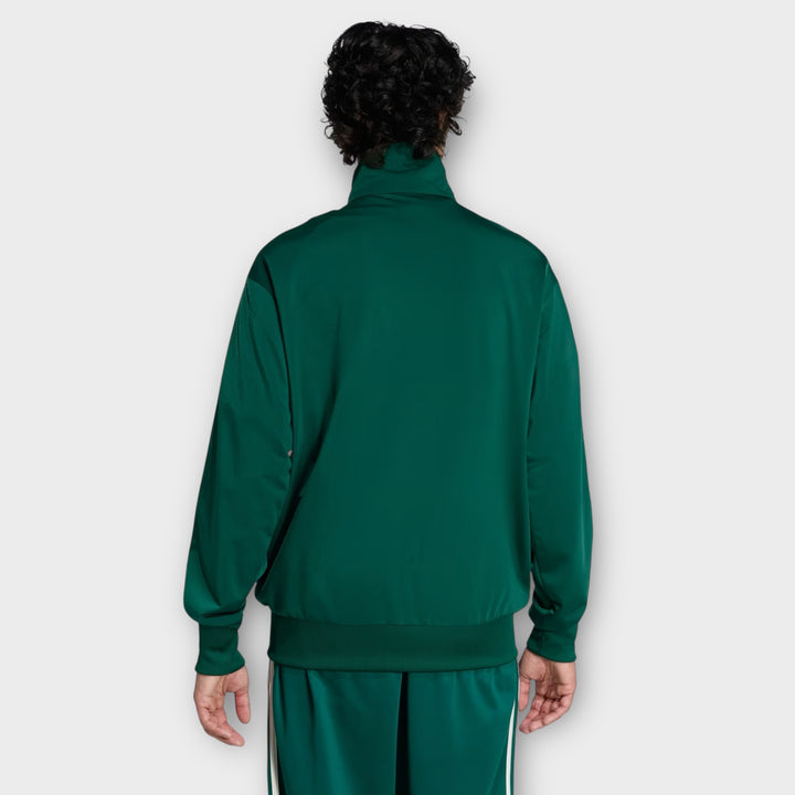Sidesyn af Adidas Firebird Tracktop i grøn med ikoniske tre striber på ærmet.