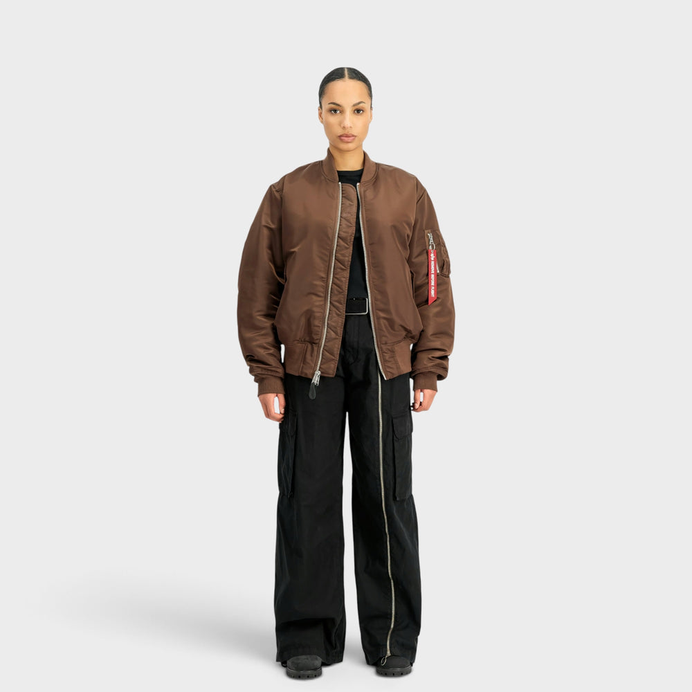 Kvindelig model i helfigur med Alpha Industries MA-1 Heritage Bomberjakke i Powder Brown og sorte bukser.