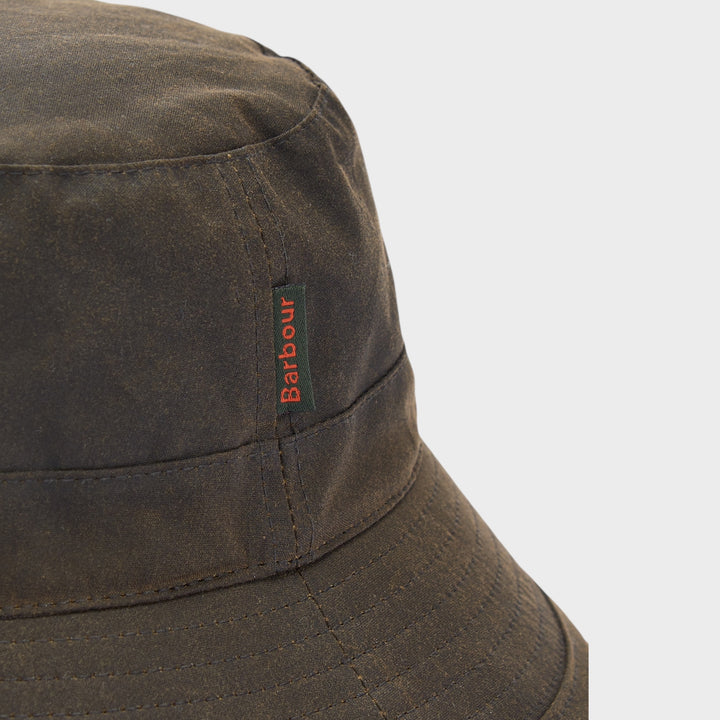 Close-up af vævet Barbour flag-label og voksbehandlet bomuld på grøn bucket hat

