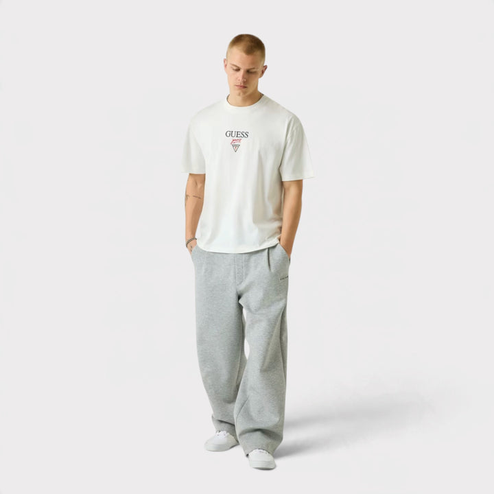 Guess Jeans Printed Logo T-Shirt i White – vist forfra på model i helfigur med grå bukser