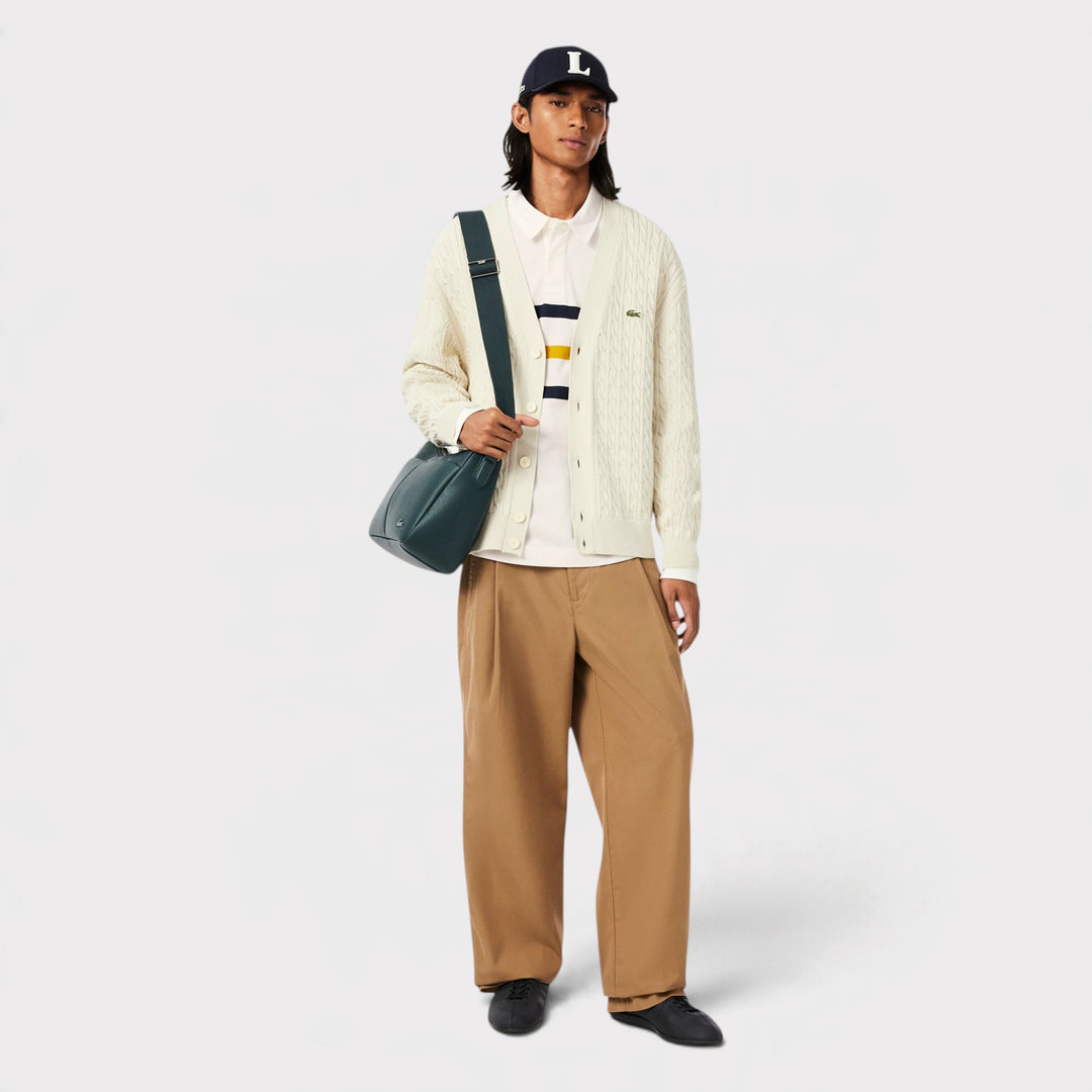 Lacoste Rugby Polo i Flour på model i helfigur med lys cardigan, kasket og grøn taske