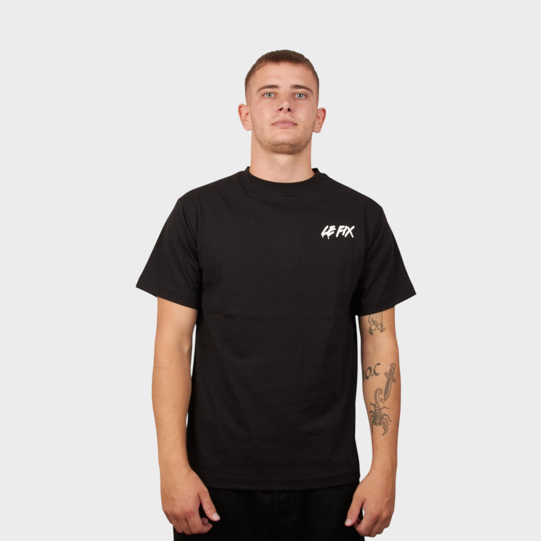 Model iført le fix tee i sort med Le Fix spray tryk på fronten