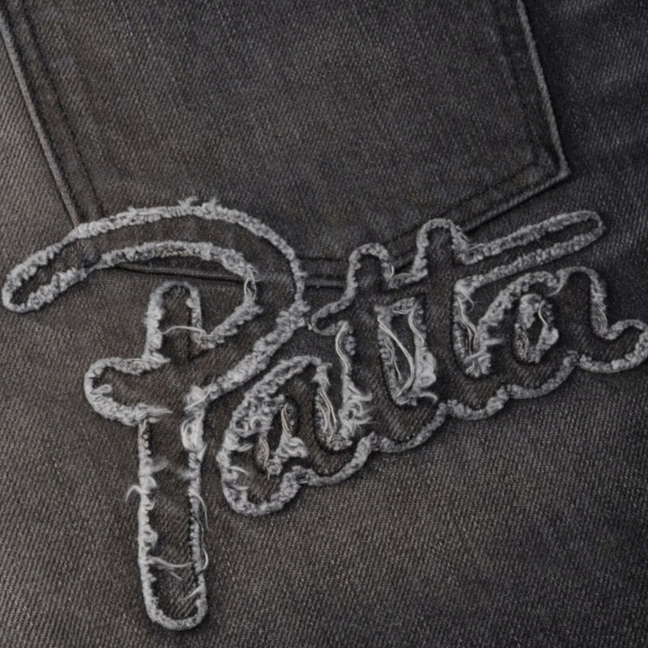 Close-up af Patta Script-applikation baglomme og læderlabel på sorte baggy jeans