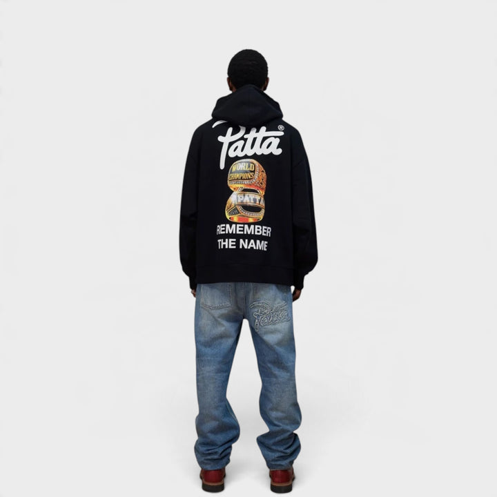 Patta Championship Hoodie i Sort vist bagfra på model med stort grafisk rygprint