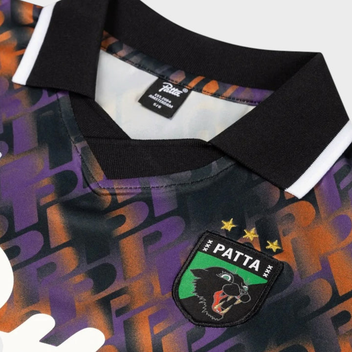 Close-up af polokrave Patta Football-badge og Lobi Libi-broderi på jerseyen