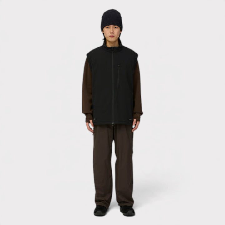 Snow Peak Breathable Insulated Vest i sort på model i helfigur med sort hue og brune bukser