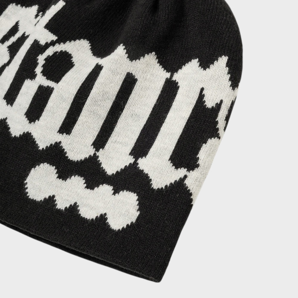 Skråt nærbillede af lyst Stan Ray-logo og strik på den sorte Logo Beanie