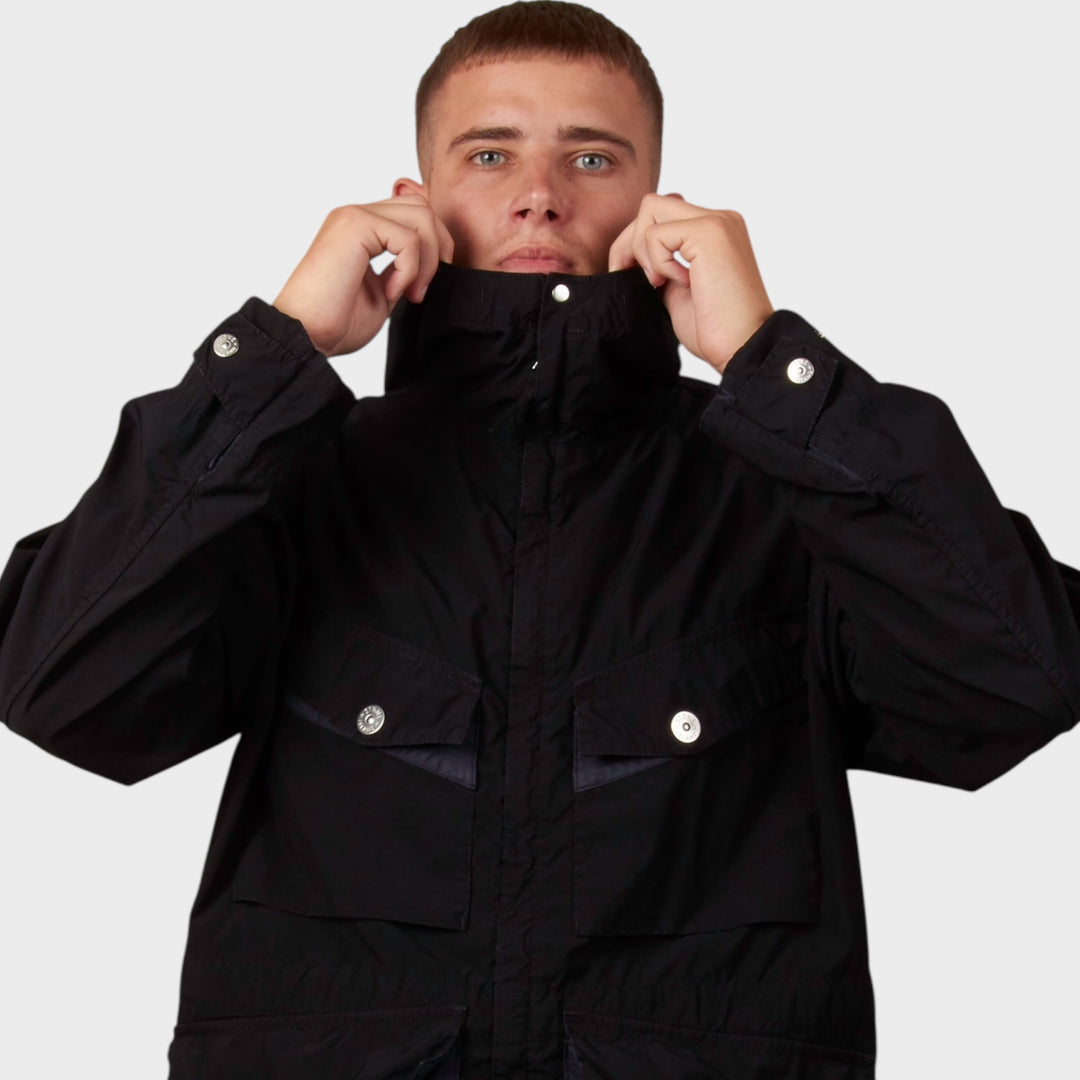 Model iført Stone Island Light Compact Touch Poly-TC Jakke i navy – frontdetalje fra midten og op, med lynlås og stofstruktur.
