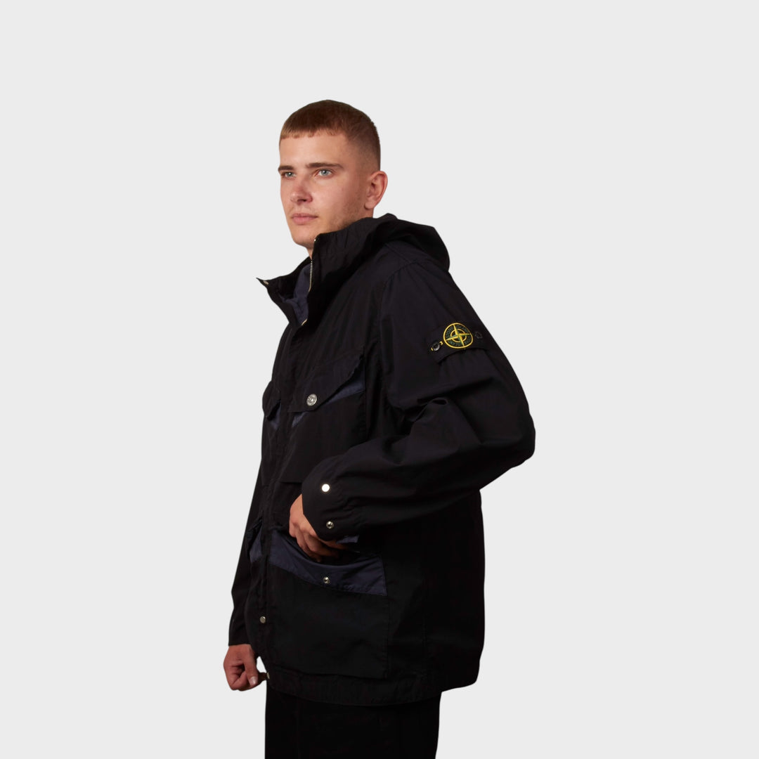 Model iført Stone Island Light Compact Touch Poly-TC Jakke i navy set fra siden i en let vinklet position.
