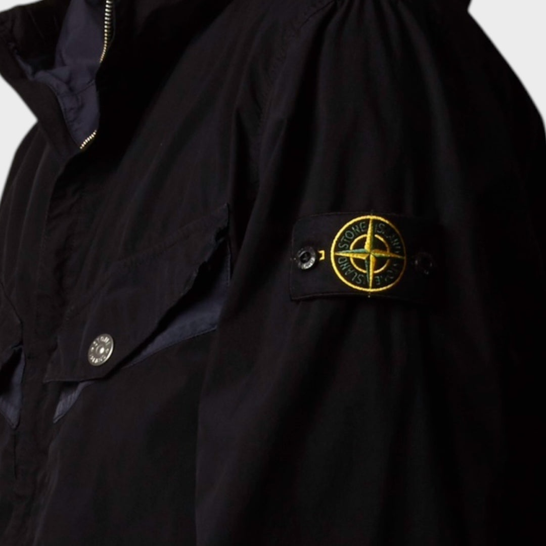 Detalje af Stone Island Light Compact Touch Poly-TC Jakke i navy set fra siden, med lynlås og stofstruktur.